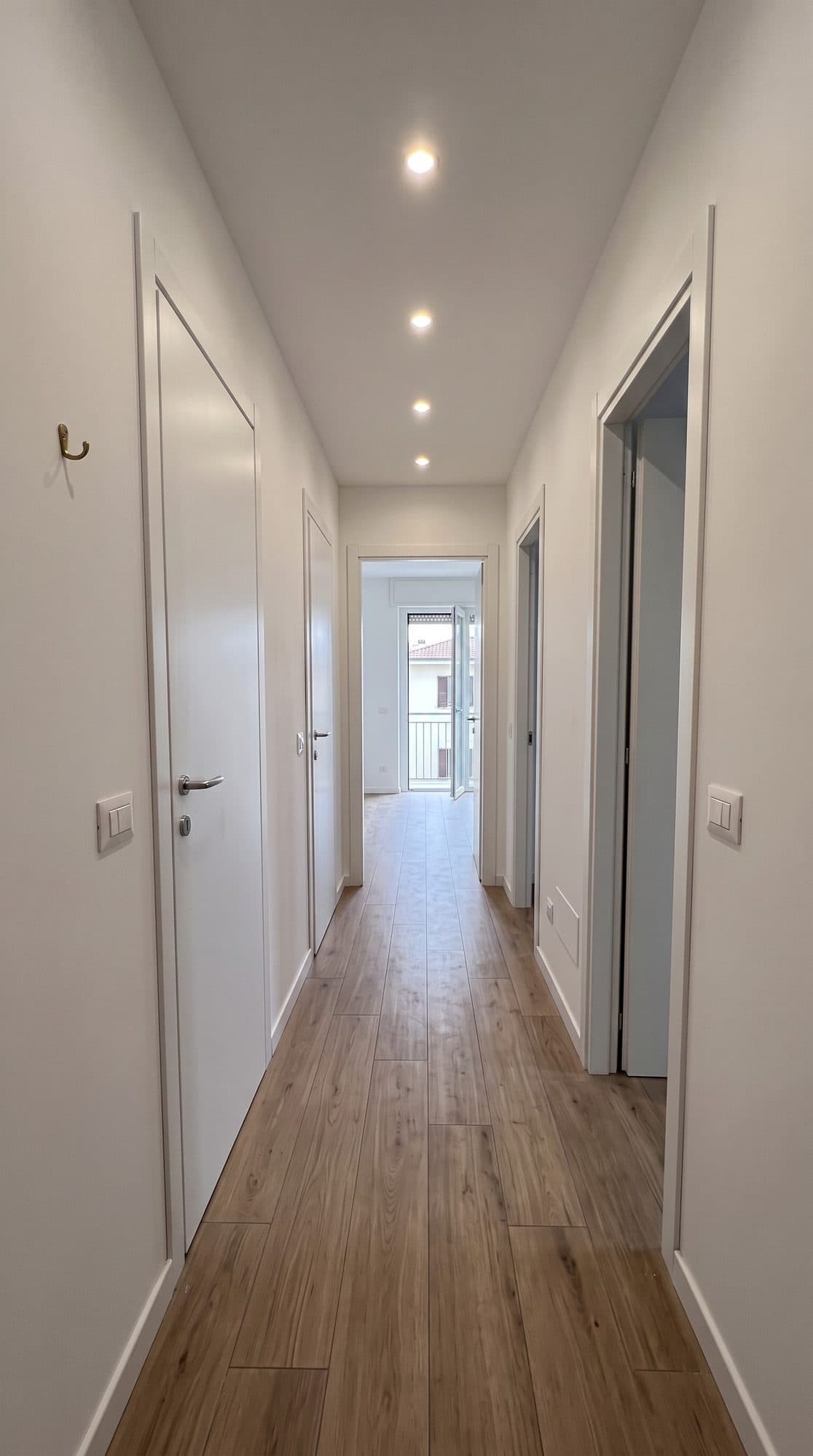 Corridoio dopo la ristrutturazione, con porte filomuro bianche e faretti a soffitto