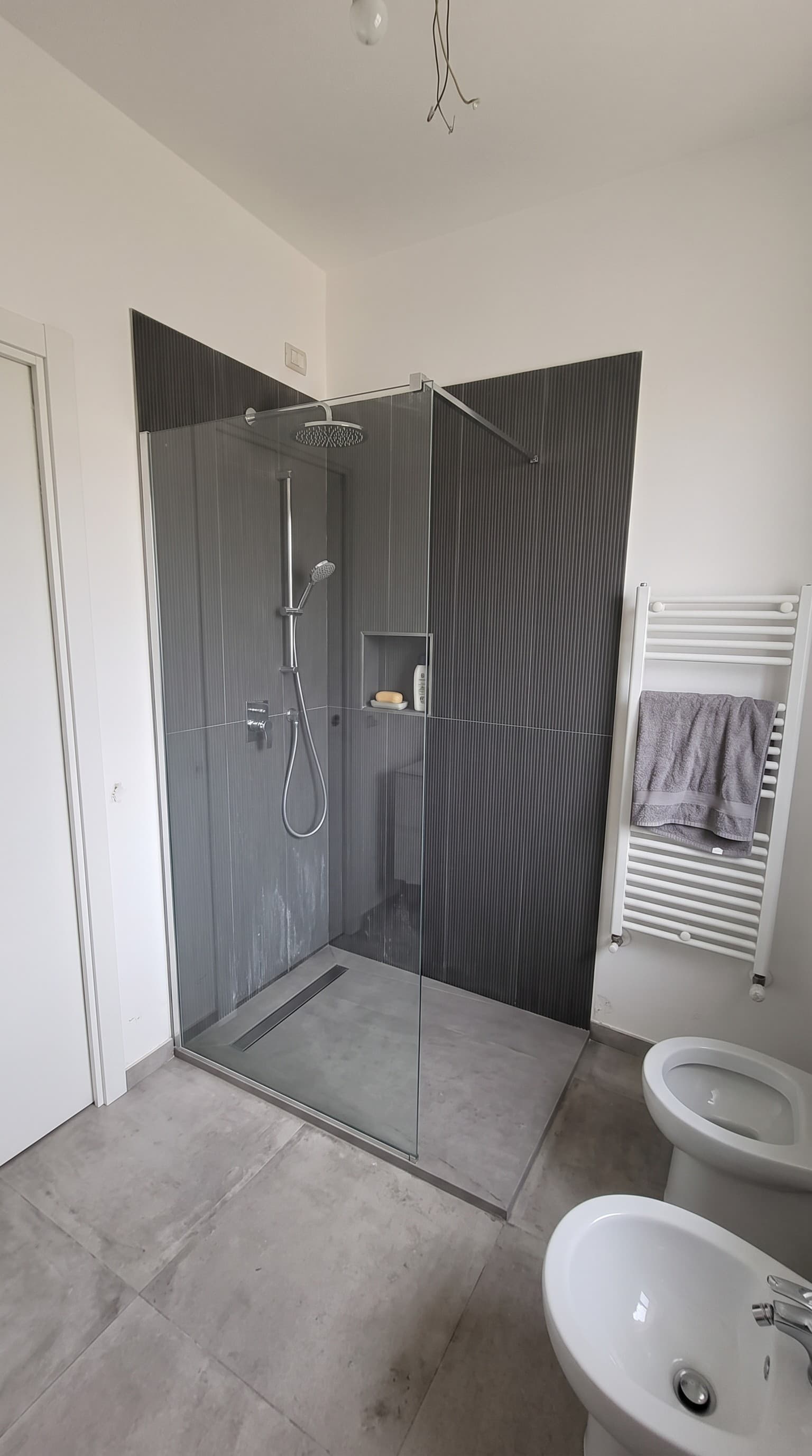 Doccia walk-in con piastrelle grigie a listelli e scaldasalviette, bagno rifatto
